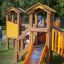 Alpha playhouse with slide na travnatém hřišti, kde si hrají děti.