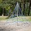 Small Powerclimber climbing net v parku se stromy v pozadí.