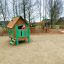 Děti si hrají na dřevěné herní sestavě Britta's Playhouse s lezeckou stěnou a skluzavkou.