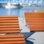 Venkovní Montpellier Deck Chair u řeky s modrým mostem v pozadí.