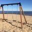 Double Safety Seat double swing umístěný na písečné pláži u moře