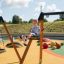 Dítě si užívá jízdu na Double Safety Seat double swing na barevném hřišti.