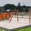Double Safety Seat double swing na pískovém hřišti se skluzavkou a lezeckými konstrukcemi.