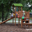 Triangle Modern Nature wooden playhouse with slide v prostředí parku