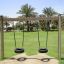 Wooden Tire double swing v parku s palmami v pozadí.
