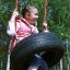 Dítě si užívá Wooden Tire double swing v parku