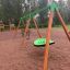 Zelená Swing Seat GBNS na dřevěné sestavě na hřišti v parku.