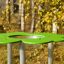 Clover Play Table v prostředí parku se zelenou horní částí a kovovými nohami.