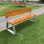 Tallin Bench w/ Backrest na travnatém pásu poblíž chodníku.