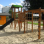 Venkovní herní vybavení Romping Cottage se skluzavkou, lezeckými sítěmi a dřevěným domečkem.