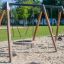 Swing Frame 1(BNS) +1 (double swing) na pískovém hřišti s kruhovým sedátkem.