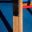 Vertical wooden ladder s kovovými konzolami na hřišti.