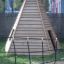 Ural climbing net před dřevěnou pyramidovou konstrukcí na hřišti.
