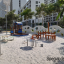 Villa sandbox with a playhouse na moderním hřišti se stromy a budovami v pozadí.