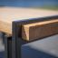 Detail Thor table s kovovým rámem a dřevěnou deskou.