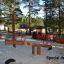 Dřevěné Nature Seesaw na hřišti obklopeném stromy.