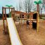 Jungle castle with slide na dětském hřišti se stromy v pozadí.
