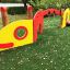 Baby Caterpillar wooden playhouse v červené a žluté barvě s kruhovým oknem a malou lezeckou plo