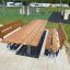 Venkovní Table & Bench Steel Construction umístěný v rekreační oblasti s trávou a herními prvky