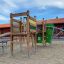 El Dorado wooden playhouse s klouzačkou a lezeckým rámem na hřišti.