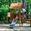 Galapagos wooden playhouse with slide a děti si hrající venku v lesním hřišti