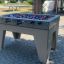 Football Table Game stolní fotbal s modrými a červenými figurkami na venkovní dlažbě.
