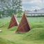Herní zařízení Tipi Nature wooden house z přírodního dřeva na travnatém poli.