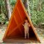 Dítě stojící uvnitř Tipi Nature wooden house na hřišti v lesním prostředí