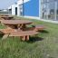 Round table & benches v travnatém venkovním prostoru poblíž moderní budovy.