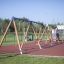 2+2 multiple swing umístěný na hřišti s gumovým povrchem a lezeckou stěnou v pozadí