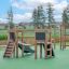 Hrací domek Mini Play II se skluzavkou na zeleném povrchu hřiště, dřevěné herní vybavení pro děti