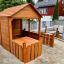 Wooden Garden Playhouse w/ Fencing v prostředí zahrady za domem.