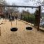 Double swing umístěný na pískovém hřišti.