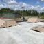 Venkovní skatepark s prvky Double Quarter-Pipe a sousedními rampami.