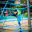 Dítě šplhající na Powerclimber climbing net na hřišti.