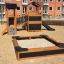 Dřevěná herní sestava Sandbox Nature se skluzavkou a mostem v městské oblasti.