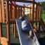 Dítě si hraje na skluzavce Nature Ship Sandbox, wooden playhouse.