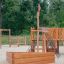 Venkovní dřevěná herní konstrukce s pískovištěm Nature Ship Sandbox na hřišti.