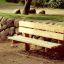 Larchwood Bench umístěný v parku vedle kamenné zdi.