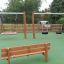 Larchwood Bench na hřišti s houpačkami v pozadí.