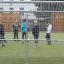 Děti hrající fotbal na sportovním hřišti Goal obehnaném kovovým oplocením.