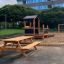 Larchwood Table & Bench na dětském hřišti poblíž pískoviště a herní konstrukce.