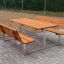 Venkovní Table & Bench sestava s dřevěnými sedáky a kovovým rámem na dlážděném povrchu.