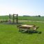 Table & Bench Quadro v zeleném parkovém prostoru s dětským hřištěm v pozadí.