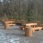 Table & Bench Nature v parku s dřevěnými stoly a lavicemi.