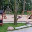 Sestava hřiště Playhouse Nature s prolézačkami a skluzavkami v parku.