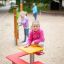 Dívka sedící na Square bench and table na hřišti.