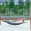 Hammock s dřevěným rámem a černou sítí na hřišti.