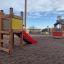 Dřevěné Toddler Tower Slide s červenou skluzavkou na hřišti.