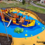 Bounty ship with slide na barevném hřišti, oplocený a obklopený budovami.